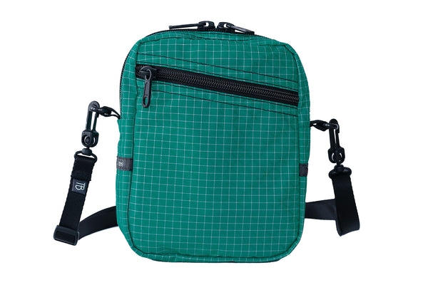 An Everyday Cubelet in Kelpie Halcyon (bluish-green with a white grid) with a front zipper.